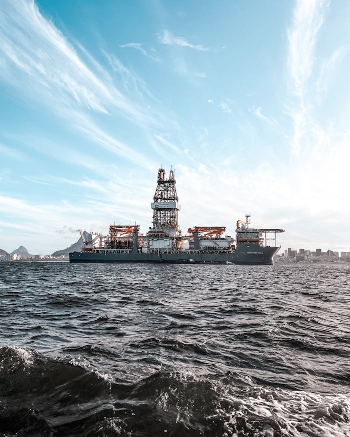Large offshore oil rig ship on open sea with dramatic sky and skyline.