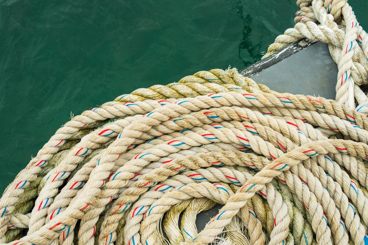 Intricate coiled rope on a boat deck with a view of the serene sea.