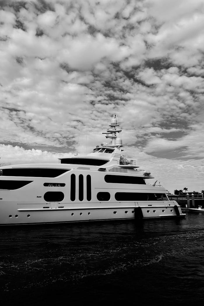A striking black and white image of a luxury yacht against a dramatic cloudy sky.