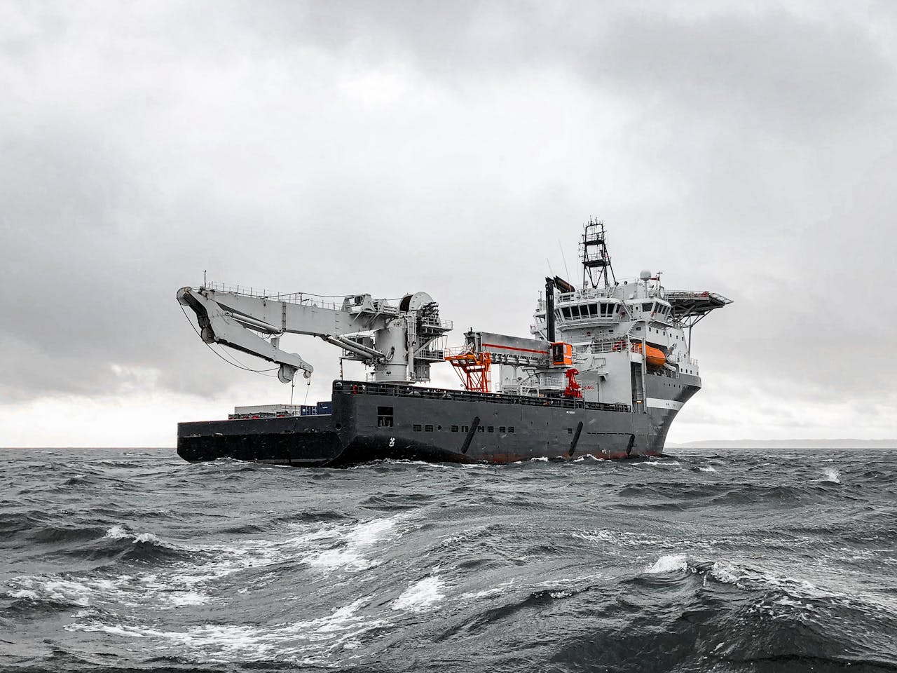 A large industrial ship cruising through a stormy sea under a cloudy sky, showcasing marine engineering and transportation.