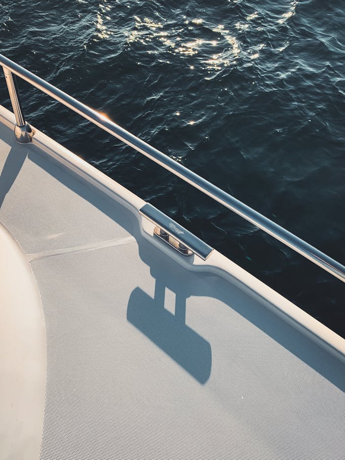 Capture of a yacht deck with metal railing and sparkling ocean.