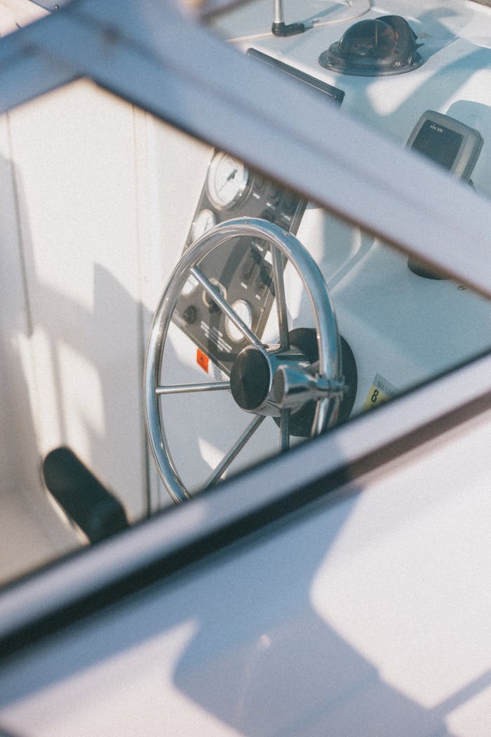 Detailed photo of a yacht's helm featuring stainless steel steering wheel and controls.